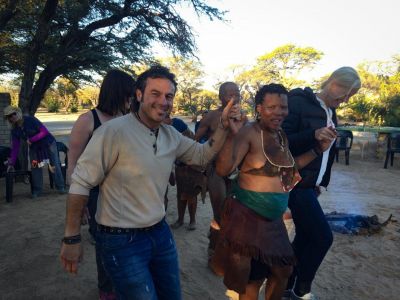 Image of three people dancing two from North America, with an indigenous African tribe member at an event. 